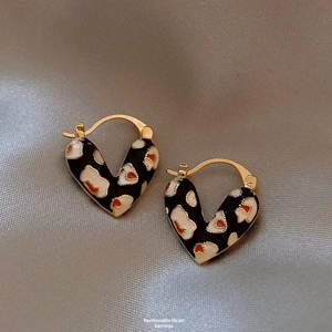 Macro shot of gold-plated heart hoop earrings with leopard print enamel on fabric