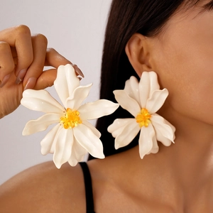 Detail shot of large 3D white acrylic flower earrings with yellow crystal stamens