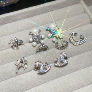 Close-up of elegant silver ear cuffs with zircon heart and pearl bird charms