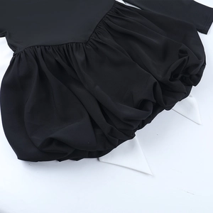 Détail de l'ourlet d'une robe noire à col carré avec doublure plissée blanche évasée