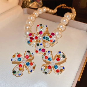 Elegant jewelry set with pearl necklace and colorful gemstone cross pendants in a box