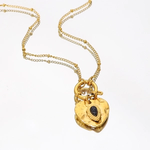 Gold heart necklace with black marble gemstone and hammered texture on white background
