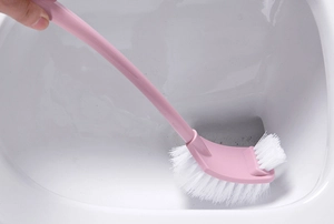 Detail showing the curved pink handle toilet brush cleaning hard-to-reach toilet rim areas