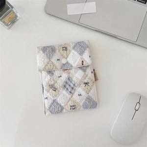 Close-up of quilted bear pattern organizer bag with resin button closure on a white desk