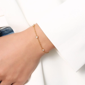 Gros plan d'un bracelet en titane doré avec trois zircons sertis clos au poignet