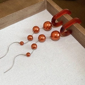Detail view of long tassel earrings with amber acrylic C-hoops and gradient faux pearls