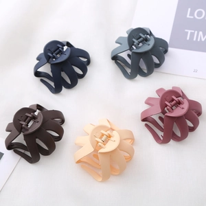Five matte 8cm octopus hair claws in navy, blue, brown, pink, and rose on white fabric