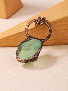 Detail of a green fluorite raw stone pendant with handmade bronze edge wrapping