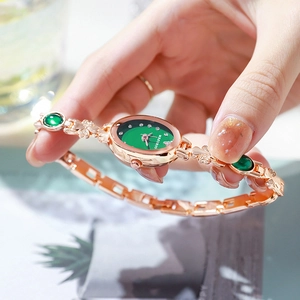 Luxury women's quartz watch with oval green dial and emerald-style gold bracelet