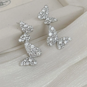 Detail showing silver butterfly earrings with sparkling crystals on white silk
