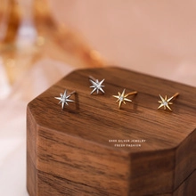 Macro view of gold and silver S925 sterling silver star stud earrings on walnut box