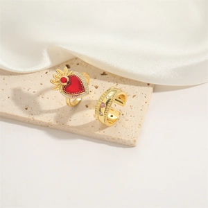 Golden heart ring with red gemstone and adjustable band on soft white silk fabric