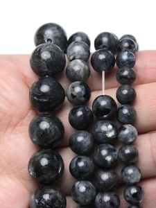 Close-up of natural dark grey labradorite beads in various sizes on hand