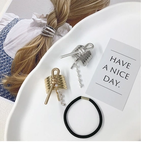 Detail of spiral metal hair hook with delicate pearl fringe and black elastic band