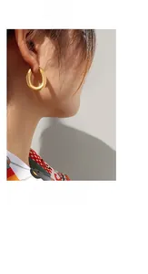 Gros plan de boucles d'oreilles dorées mates en forme de U sur mannequin, style épuré
