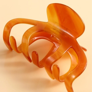 Large amber acetate shark hair claw clip for bun hairstyles on a beige background