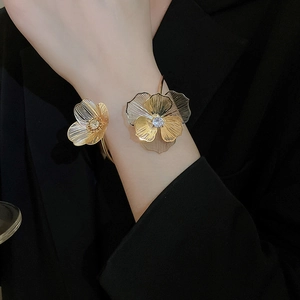 Detail of open cuff bracelet with hollow gold flower and sparkling crystal center