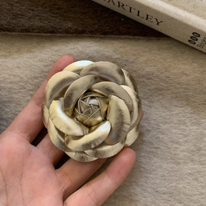 Macro detail of golden camellia brooch with layered textured petals and vintage finish