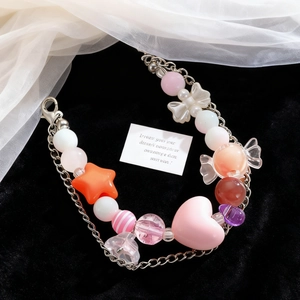 Detalle de pulsera de cuentas con corazón rosa y estrella naranja sobre terciopelo negro