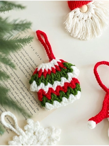 Detail of handmade crochet Christmas ornaments showing knit textures of tiny sweaters and snowflakes