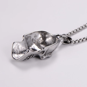 Macro view of polished silver skull pendant with vintage texture and round box chain