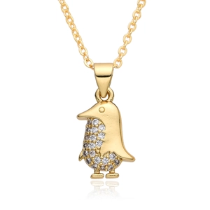 Detail of a golden penguin pendant with micro-pave crystals on a white reflective base
