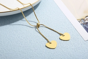 Macro view of gold snake chain necklace with dual heart pendants and adjustable slider clasp