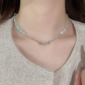 Close-up of beaded necklace with blue crystals on model wearing tweed outfit