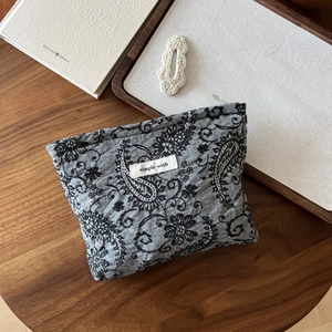 Macro shot of paisley print linen pouch with simple wish label on a vintage wood desk