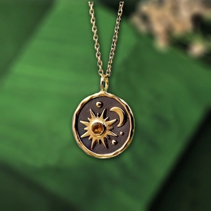 Macro shot of sun and moon coin pendant necklace with a yellow gemstone center