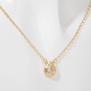 Close-up of gold pear-shaped zircon pendant necklace on a white mannequin bust