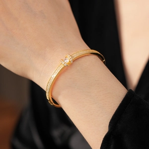 Close-up of gold-plated oval bangle with horseshoe pavé diamonds on a model's wrist
