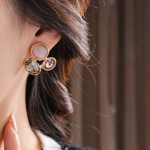 Macro shot of vintage gold earrings with pink cat-eye stone and grey gems on model