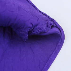 Dettaglio ravvicinato delle cuciture dell'abito in raso viola con rifinitura taglia-cuci