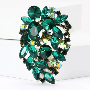 Detail of vintage emerald crystal brooch with gold metal floral cluster on white steps
