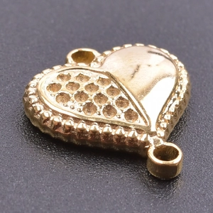 Macro shot of gold heart pendant featuring a unique split smooth and textured surface