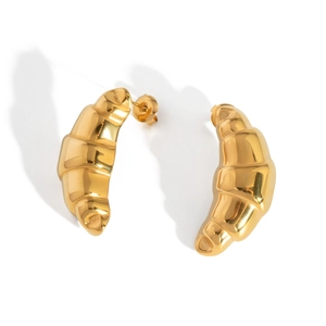 Detailed view of polished golden croissant earrings in stainless steel on white background