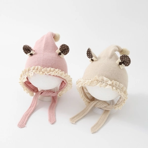 Detailed close-up of baby knit hats featuring pom-poms, lace trim, and polka dot ear details