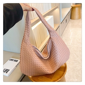 Detailed texture of a woven crescent-shaped handbag in nude pink faux leather finish