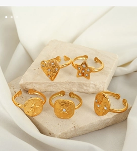 Macro detail of five gold-plated geometric rings with zircon inlay on a beige fabric