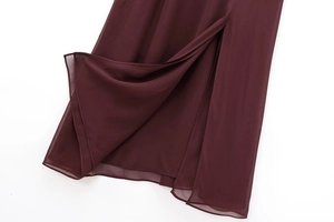 Detail of burgundy sleeveless dress featuring a high side slit and layered chiffon hem