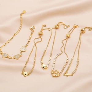Set aus fünf eleganten Goldarmbändern mit Herz, Kreuz und Sternanhängern auf Seide