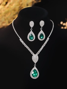 Detailed close-up of luxury bridal jewelry set with green teardrop gems and white rhinestones