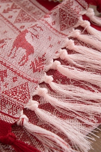 Detailed macro view of festive red and white woven fabric with reindeer patterns and tassels