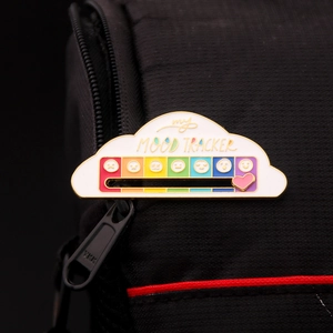 Detail of cloud-shaped enamel mood tracker pin with sliding heart on rainbow scale