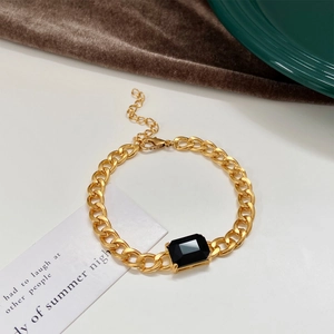 Detail of chunky gold chain bracelet with a large rectangular emerald green zircon gem