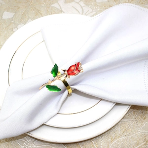 Detail of red rose napkin ring with green leaves and crystals on white cloth
