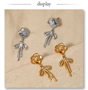 Détail de boucles d'oreilles camélia et nœud dorées et argentées avec perles et zircons