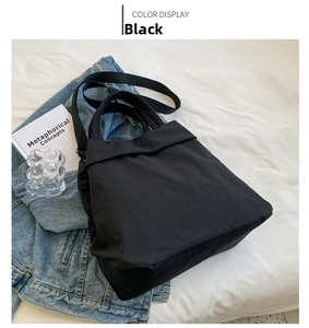 Detail of black nylon tote bag featuring adjustable strap and handles in lifestyle setting