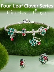 Macro shot of silver mesh bracelet with green clover and red ladybug enamel charms